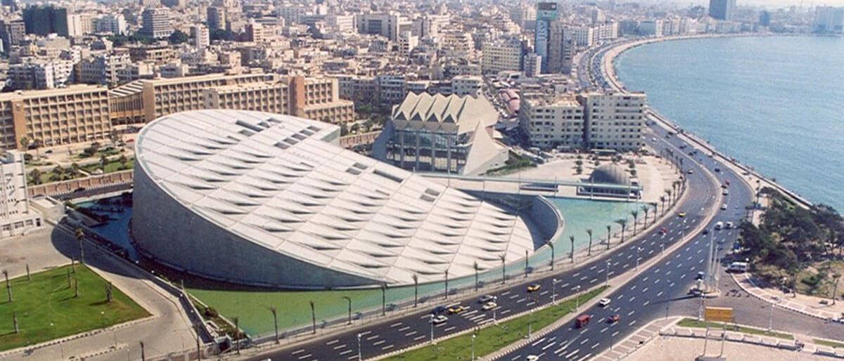 Modern exterior of the Bibliotheca Alexandrina with geometric wall carvings under a blue sky.